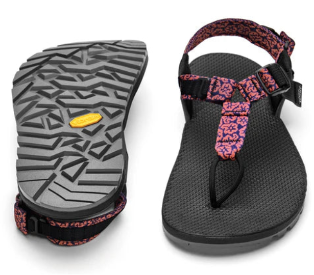 Black sandal with pink strap and textured gray sole on a white background
