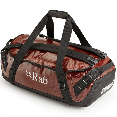 A red and black heavy-duty kitbag with a brand logo 'rab' on the side, featuring a main opening, zippered closure, and multiple handles.