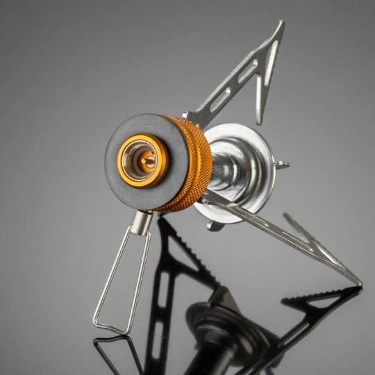 Compact camping stove with orange burner on a gray background
