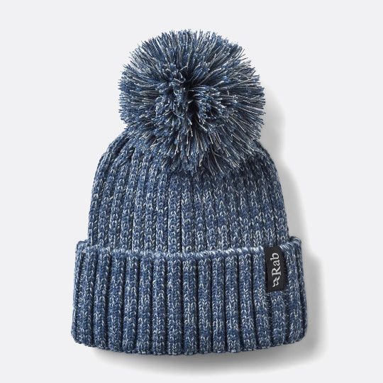 Blue knit beanie with pom-pom on a light gray background