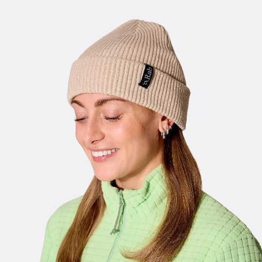 Woman wearing a lime green fleece and an off-white beanie on a white background