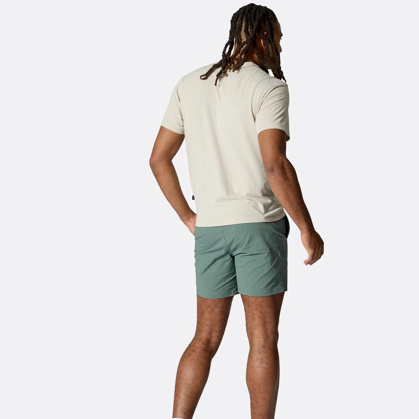 Person wearing a beige t-shirt and green shorts on a white background