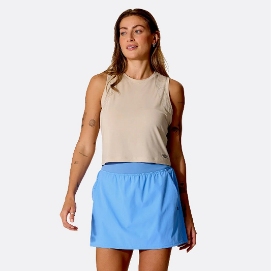 Woman wearing a beige tank top and blue skirt on a white background