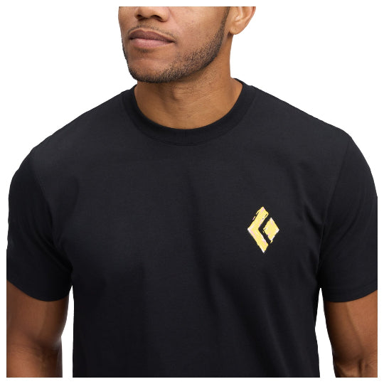 Black t-shirt with a yellow logo worn by a person on a white background