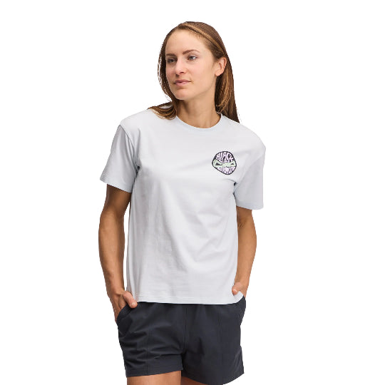 Woman wearing a white t-shirt with a logo and dark shorts on a white background