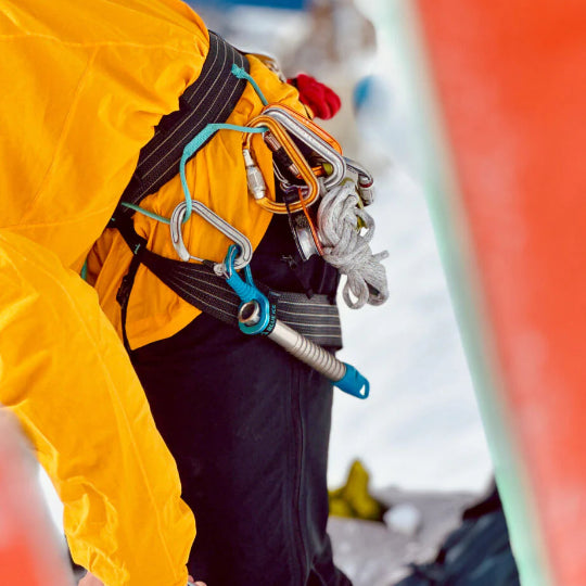 Person in a yellow raincoat with climbing gear on a snowy background