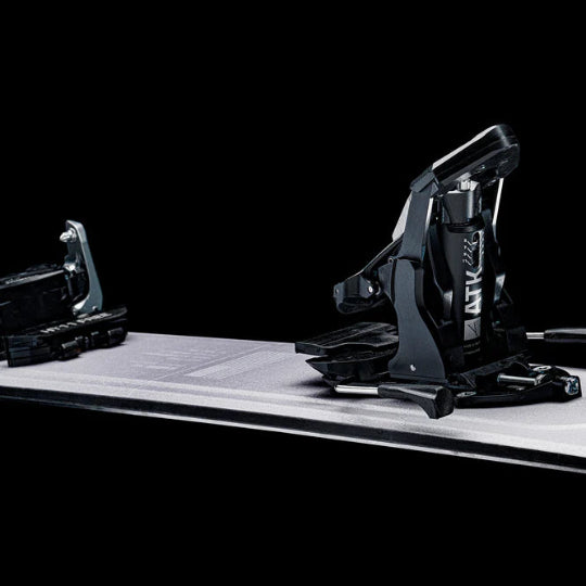 Black ski binding on a white platform with a black background