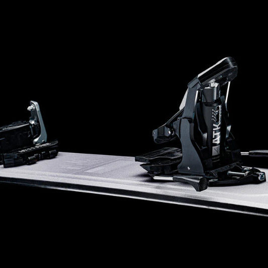 Black ski binding on a white platform with a black background