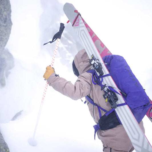 Person with skis on their back climbing a snowy mountain