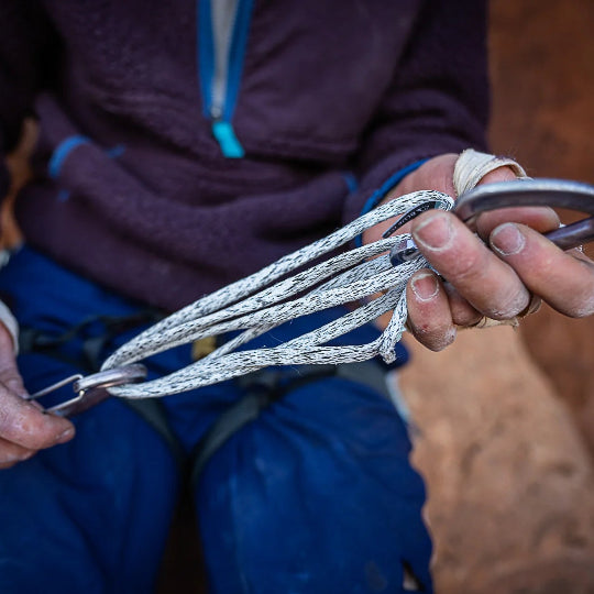 Person holding a carabiner attached to a sling with a blurred background