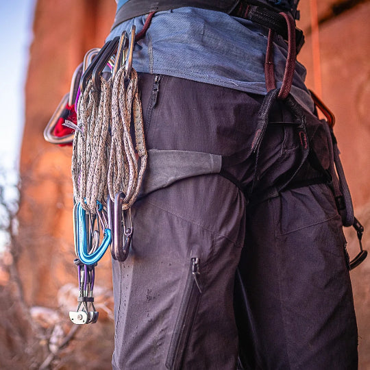 Person wearing climbing gear with ropes and equipment in a natural setting