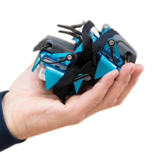 Hand holding collapsed crampon on a white background