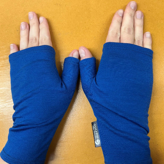 Blue fingerless gloves worn on hands with a visible brand tag on a wooden surface