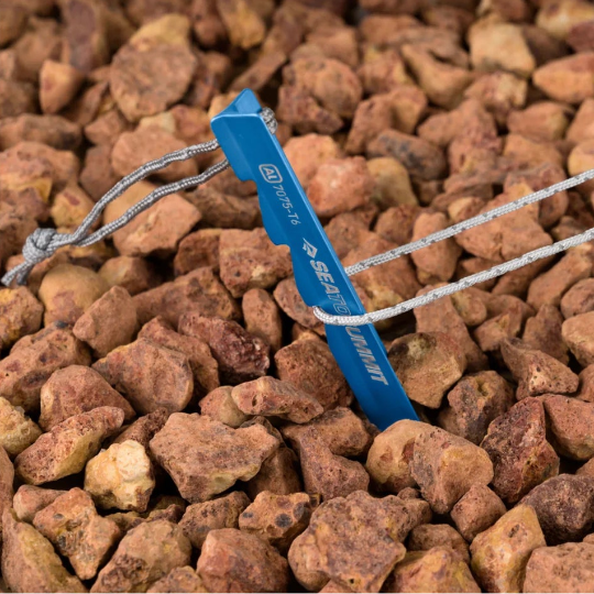 Blue tent peg with guy rope on a bed of small stones
