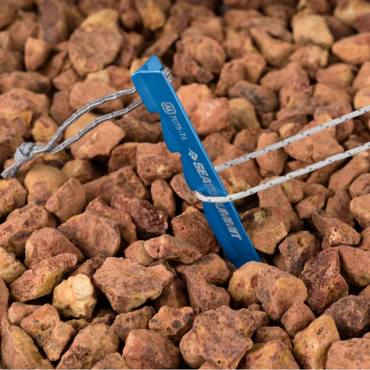 Blue tent peg with guy rope on a bed of small stones