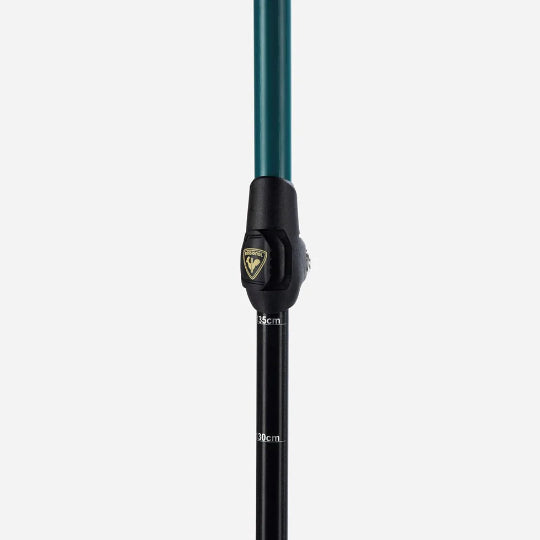 Close-up of a ski pole adjustment clasp with a black lower shaft and green upper shaft on a white background