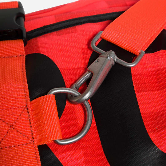 Close-up of a red and black harness with a metal clip on a white background