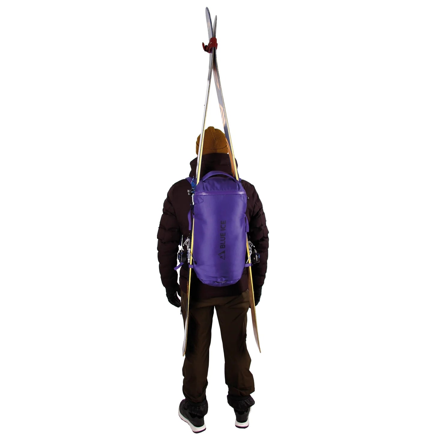 Person wearing a purple backpack with skis attached on a white background