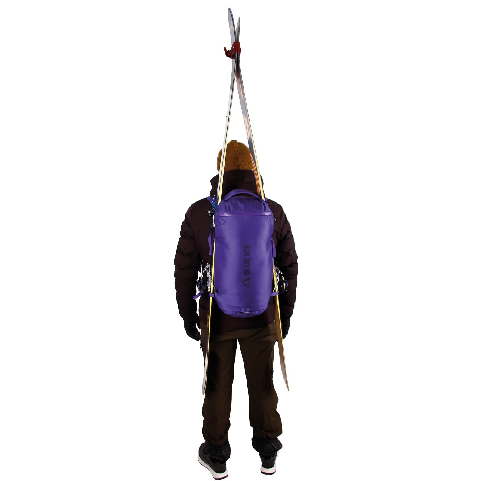 Person wearing a purple backpack with skis attached on a white background