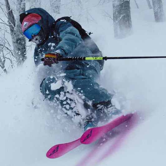 Person skiing with pink skis in a snowy forest