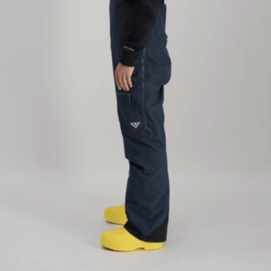 Person wearing navy blue snow pants with a logo on a gray background
