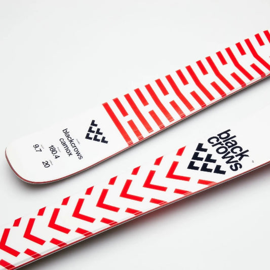 Skis with a red and white striped pattern and Black Crows logo in black on a light gray background