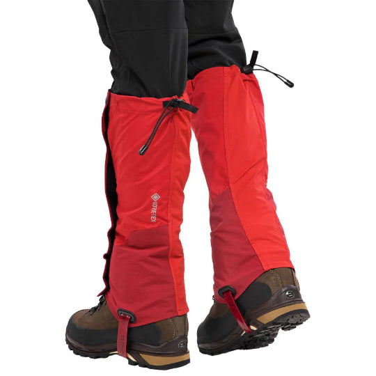 A person in black pants wearing red gaiter over brown boots on a white background