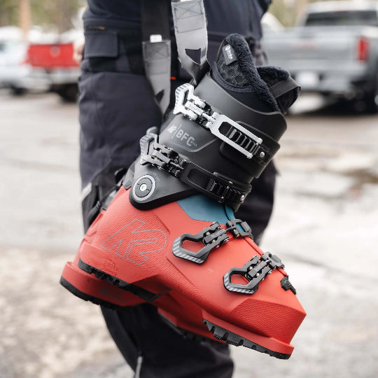 Red and black ski boot held by a person with a blurred background