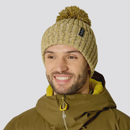 Man wearing a green beanie and jacket with 'Rab' logo on a white background