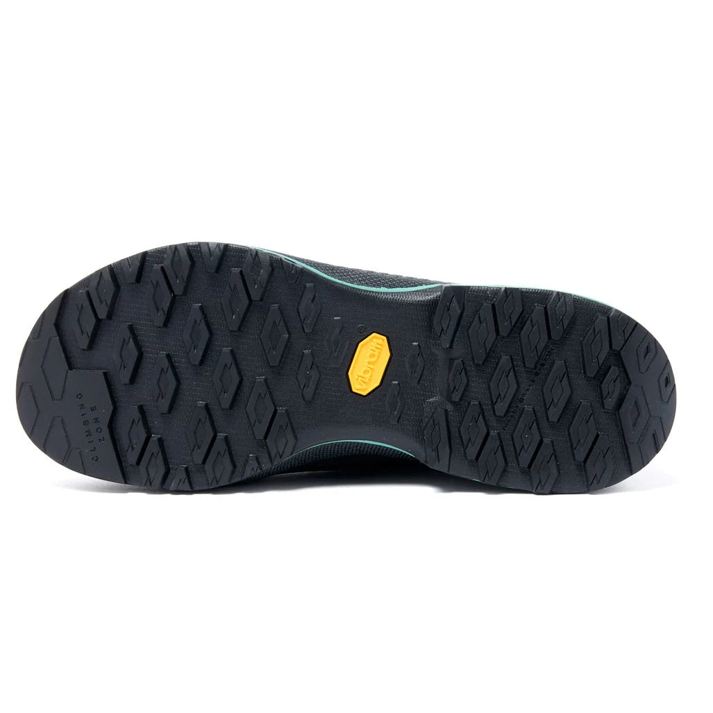 The black rubber outsole of a shoe, showing a textured tread pattern and a small yellow Vibram logo in the center, photographed against a solid white background.